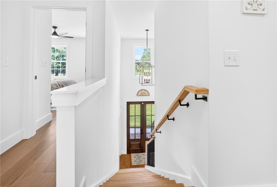 5016 Copeland Road Belton, SC 29627 - Photo 25 of 45 Hardwood stairs with a sleek wooden railing descend to a double-door entryway.