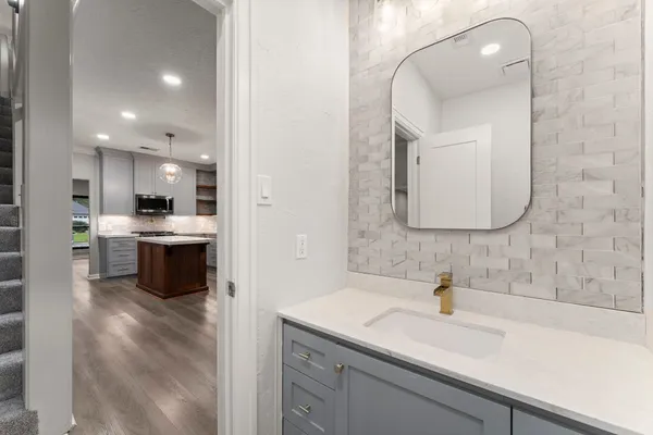 a kitchen with a sink dishwasher a refrigerator and white cabinets with wooden floor