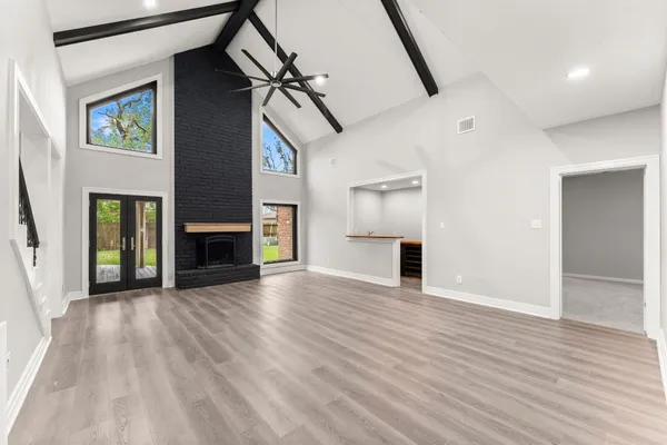 an empty room with wooden floor fireplace and windows