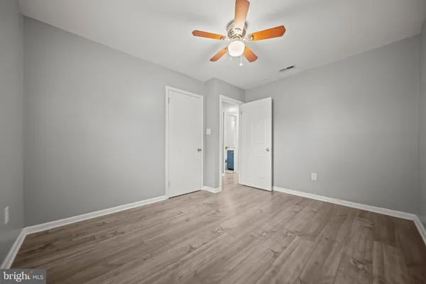 an empty room with wooden floor chandelier fan and windows