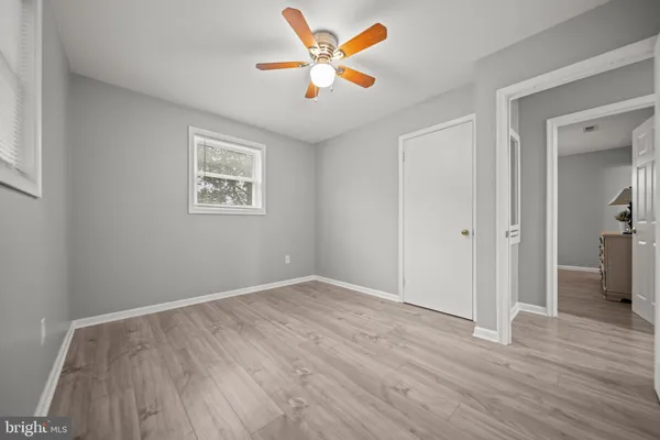an empty room with wooden floor and a ceiling fan