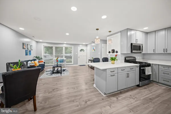 a kitchen with stainless steel appliances granite countertop a stove top oven a sink dishwasher a dining table and chairs with wooden floor