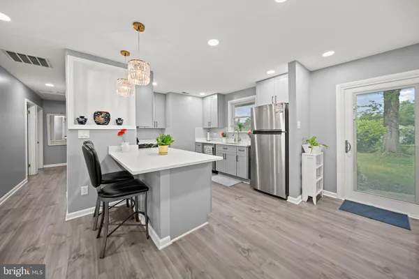 a living room with kitchen island furniture a refrigerator and a table