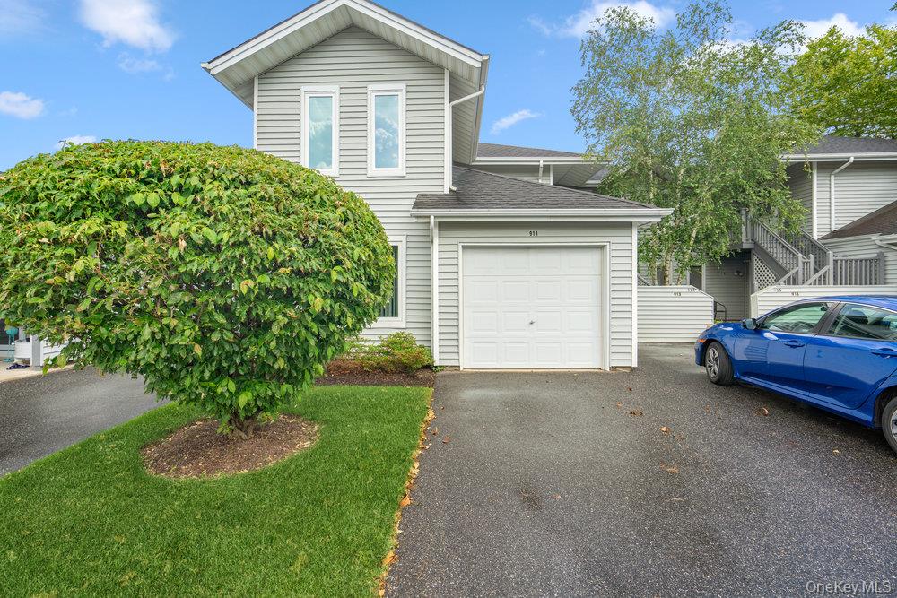 a view of a house with a yard plants and large tree