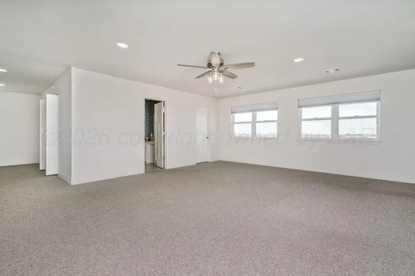 an empty room with windows and ceiling fan