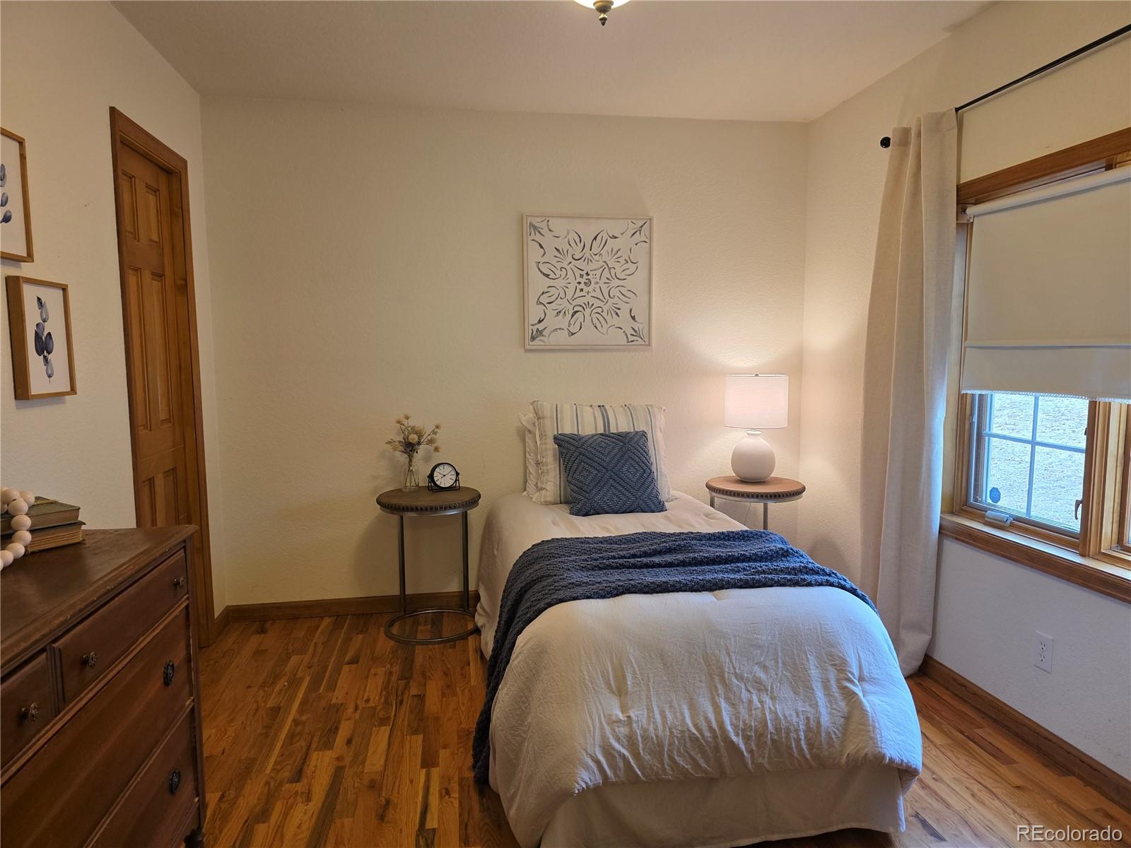 8830 South Blue Creek Road Evergreen, CO 80439 - Photo 28 of 39 a bedroom with a bed and wooden floor