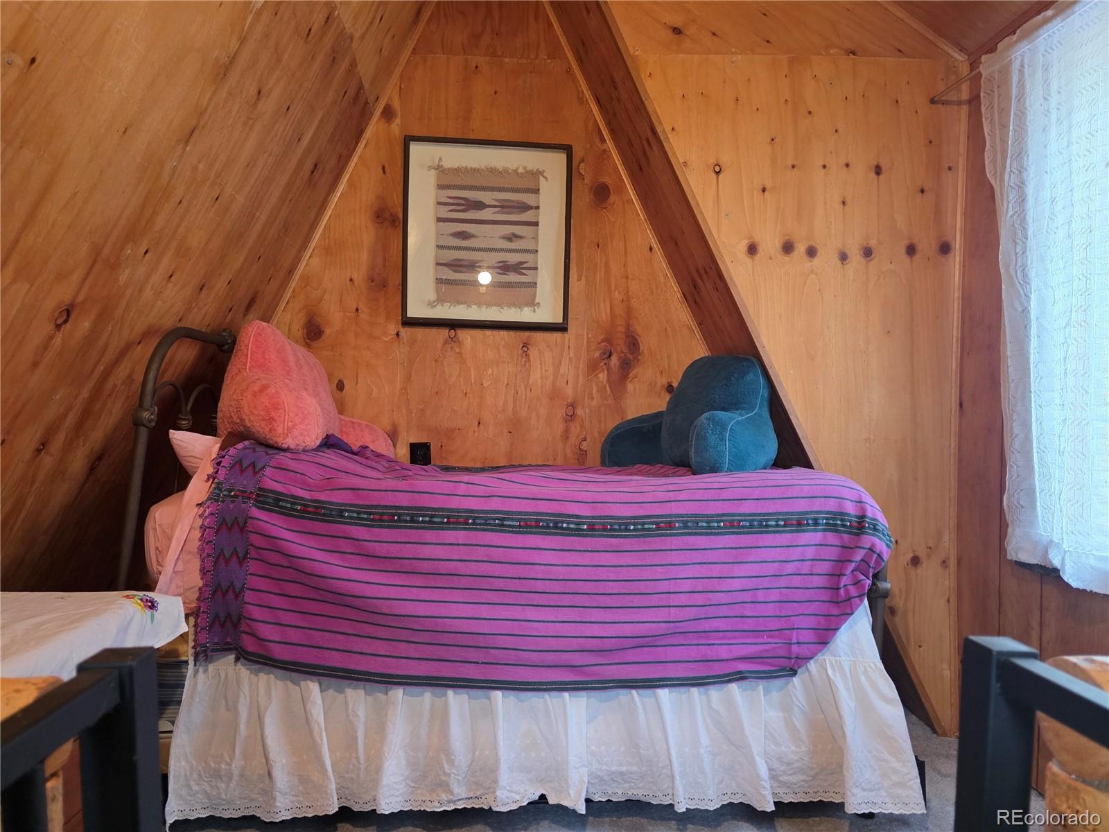 8830 South Blue Creek Road Evergreen, CO 80439 - Photo 37 of 39 a bed sitting in a bedroom next to a small window