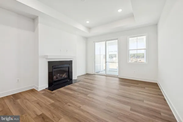 an empty room with wooden floor a fireplace and windows