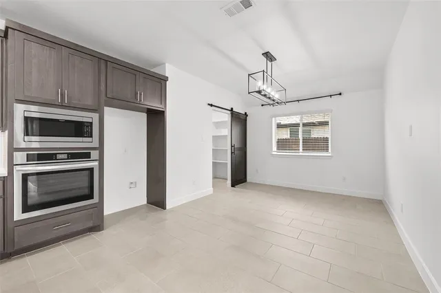a view of an empty room with a kitchen and a stove top oven
