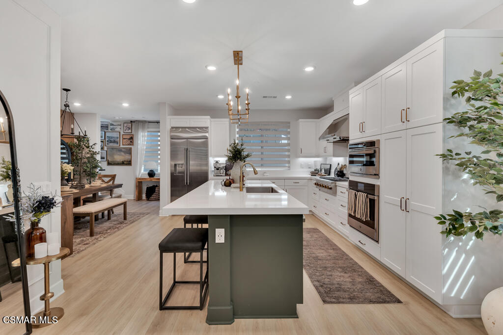 3028 Harrison Lane Simi Valley, CA 93065 - Photo 6 of 47 a kitchen with stainless steel appliances kitchen island granite countertop a refrigerator a stove a sink dishwasher and white cabinets with wooden floor