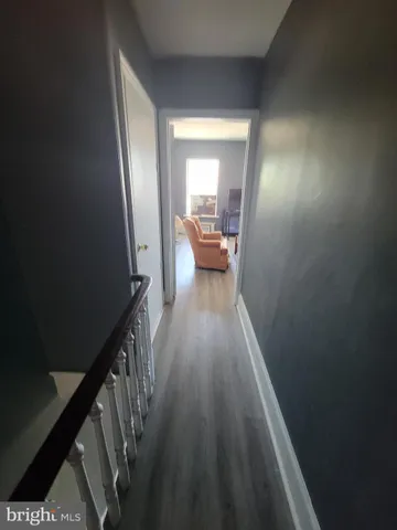 a view of a hallway with wooden floor and a bathroom