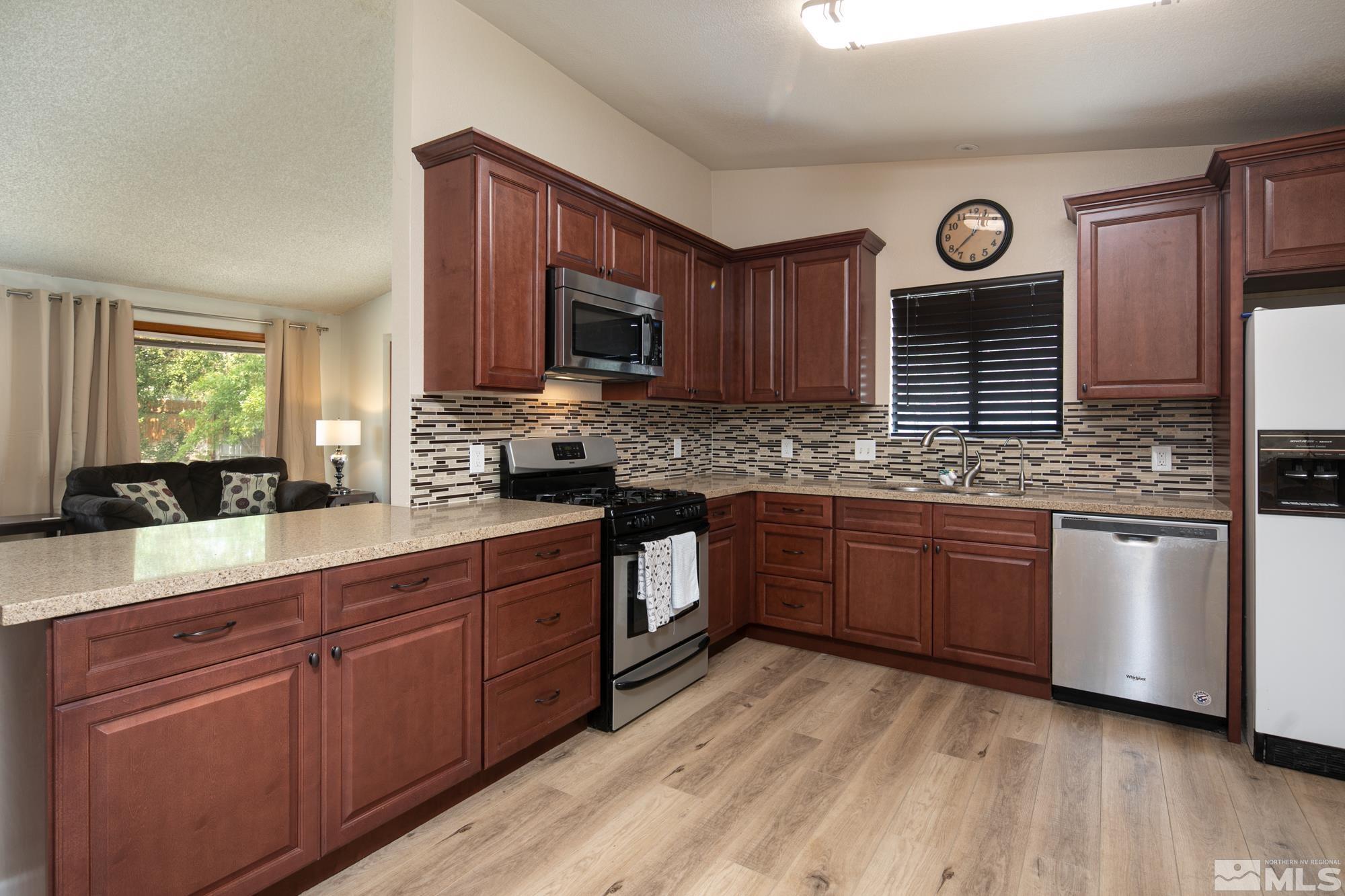 5335 Seville Court Reno, NV 89523 - Photo 9 of 31 a kitchen with stainless steel appliances granite countertop wooden cabinets a stove top oven a sink and dishwasher with wooden floor