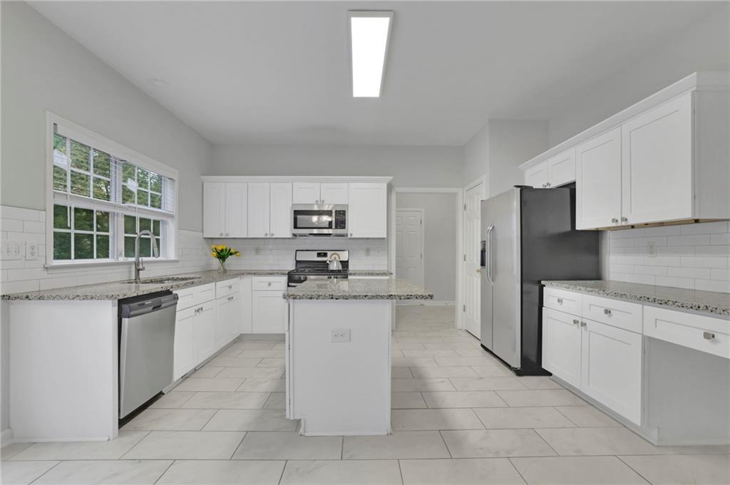 11420 Crossington Road Alpharetta, GA 30005 - Photo 13 of 39 a kitchen with stainless steel appliances granite countertop a sink counter space cabinets and a window