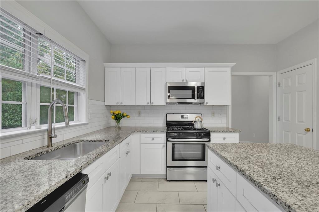 11420 Crossington Road Alpharetta, GA 30005 - Photo 14 of 39 a kitchen with granite countertop a sink stove and cabinets