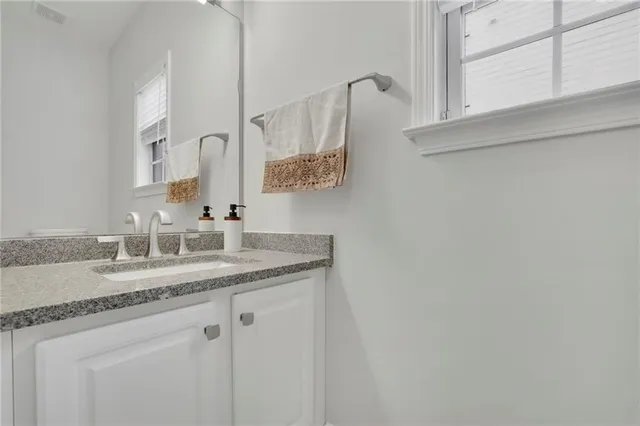 a bathroom with a granite countertop double vanity sink a toilet a mirror and shower