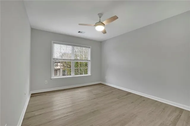 an empty room with wooden floor and windows