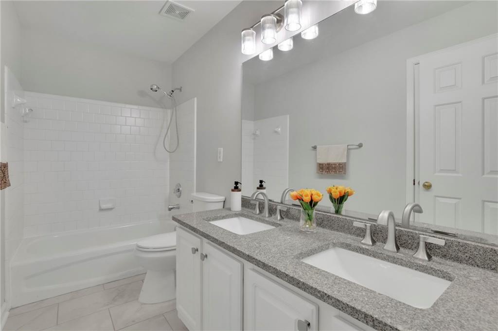 11420 Crossington Road Alpharetta, GA 30005 - Photo 22 of 39 a bathroom with a granite countertop double vanity sink a toilet a mirror and shower