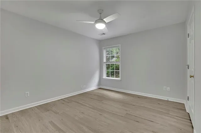 a view of an empty room with a window and wooden floor