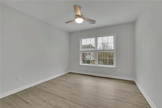 a view of an empty room with wooden floor and a window