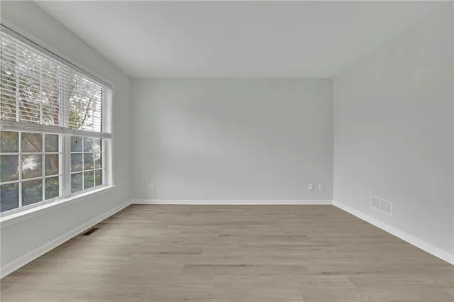 a view of an empty room with a window and wooden floor