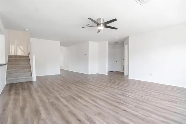 a view of empty room with wooden floor and ceiling fan