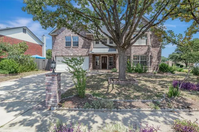 a view of a brick house with a yard and plants