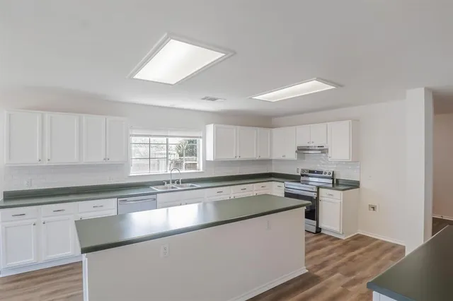 a kitchen with stainless steel appliances granite countertop a stove a sink and a refrigerator