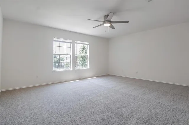 an empty room with windows and chandelier fan