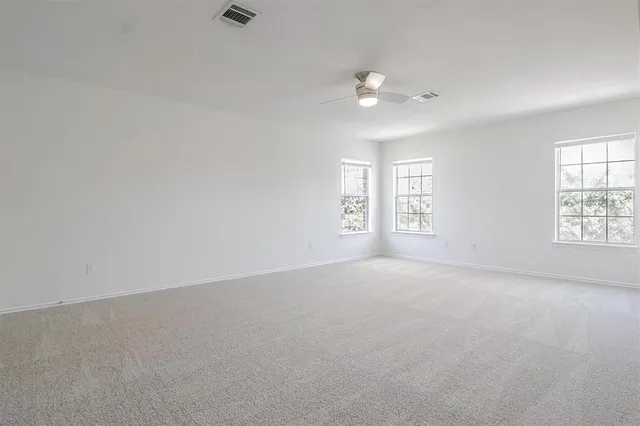 an empty room with windows and chandelier fan