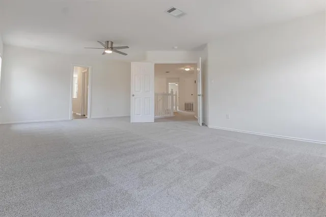 en empty room with windows and ceiling fan