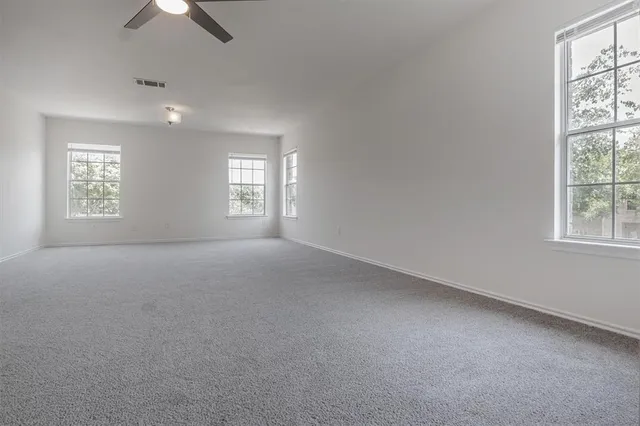 an empty room with windows and chandelier fan