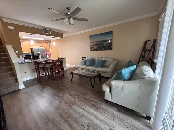 a living room with furniture and a dining table with wooden floor
