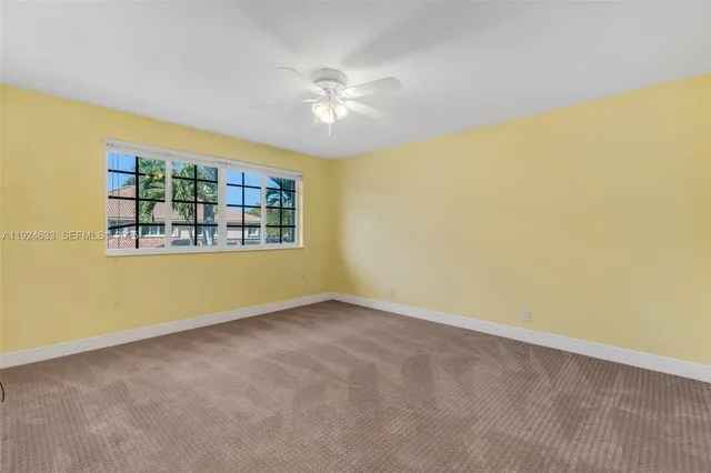 an empty room with a window and ceiling fan