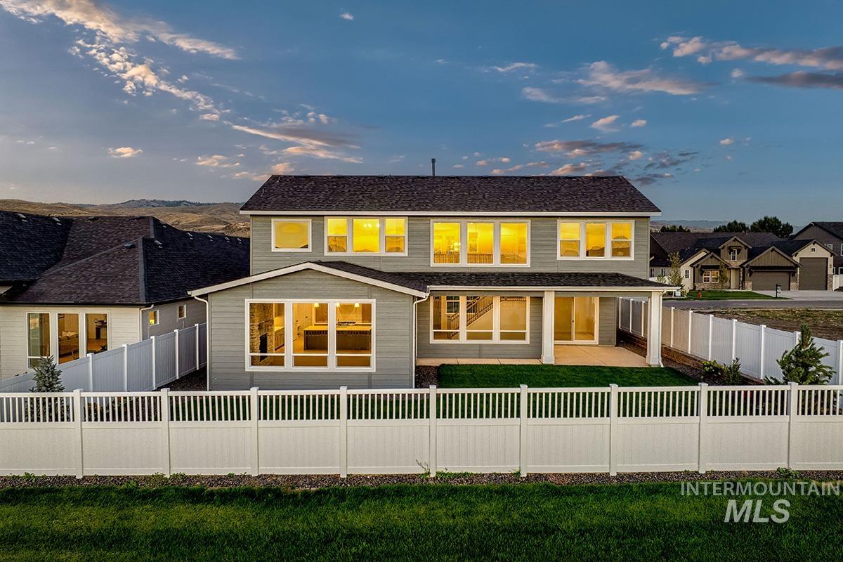 13424 North Spring Creek Way Boise, ID 83714 - Photo 31 of 43 Back of house at dusk featuring a fenced backyard, a patio area, and a residential view