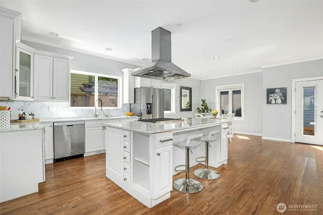 a kitchen with center island wooden floor and stainless steel appliances