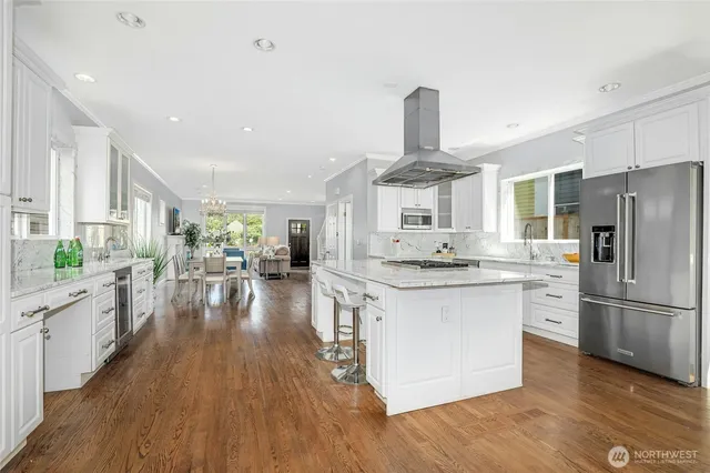 a kitchen with stainless steel appliances a refrigerator a sink dishwasher a stove and white cabinets with wooden floor