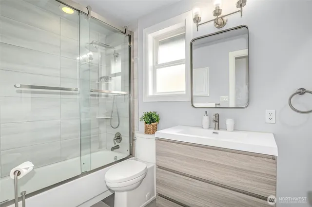 a bathroom with a toilet a sink a glass door a shower and a mirror