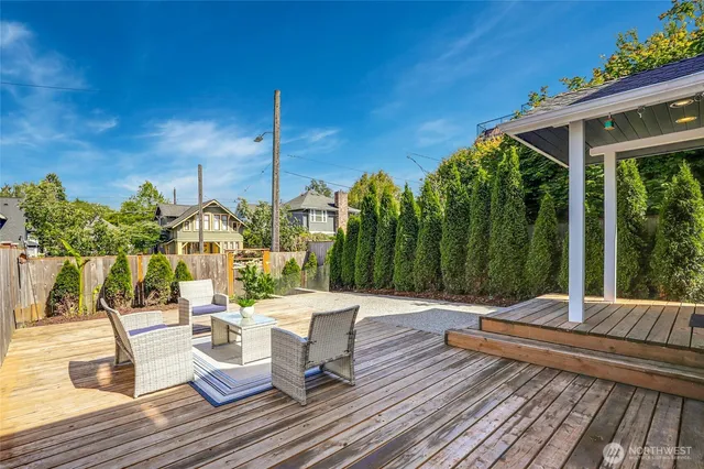 a view of a patio with wooden floor table and chairs with wooden floor and fence
