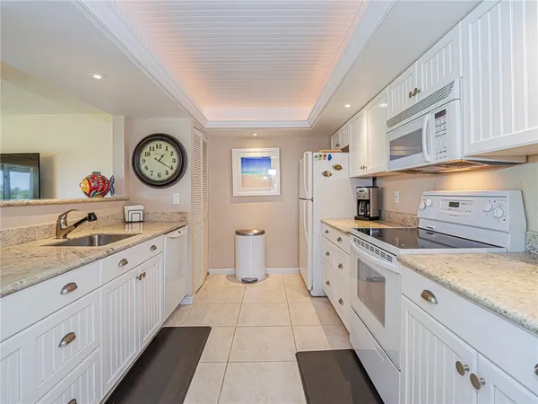 a large white kitchen with stainless steel appliances granite countertop a lot of counter space and a sink