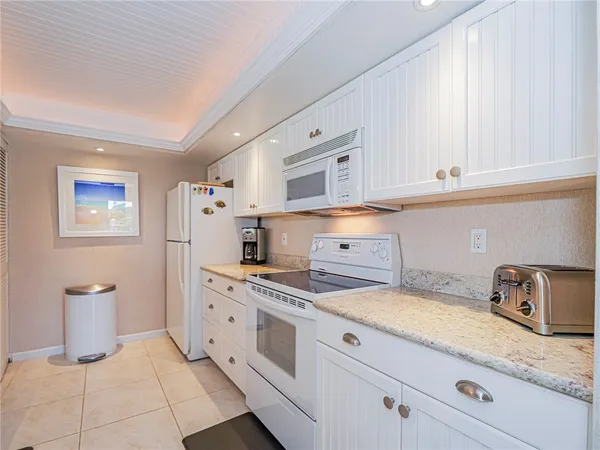 a kitchen with granite countertop white cabinets and white appliances