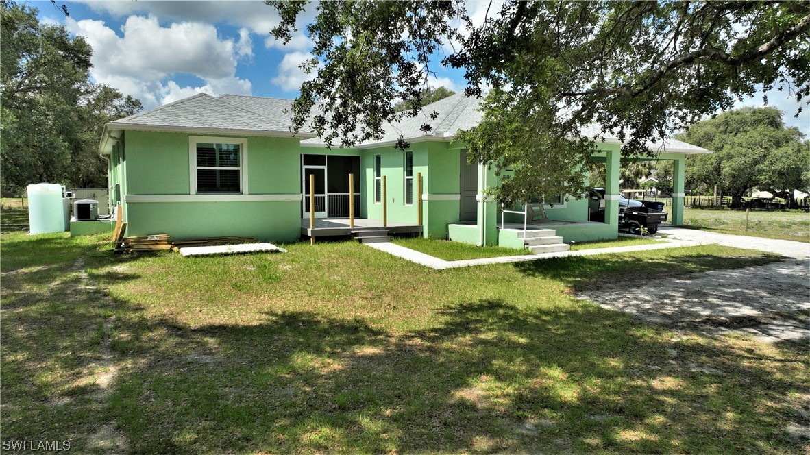23170 North River Road Alva, FL 33920 - Photo 39 of 50 a view of a house with a big yard potted plants and large tree