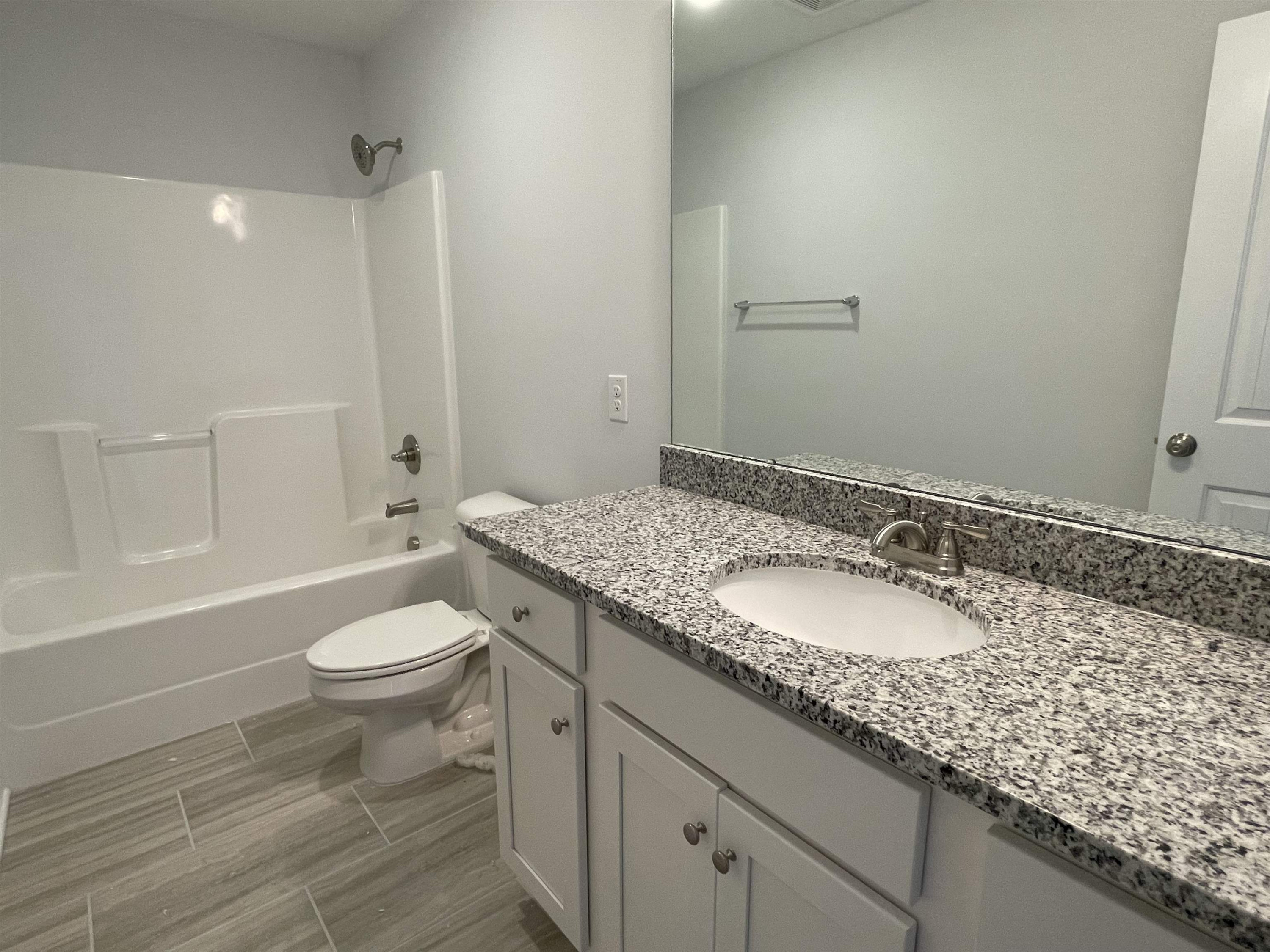 175 Devilwood Drive Four Oaks, NC 27524 - Photo 16 of 20 a bathroom with a granite countertop sink a toilet and a bathtub