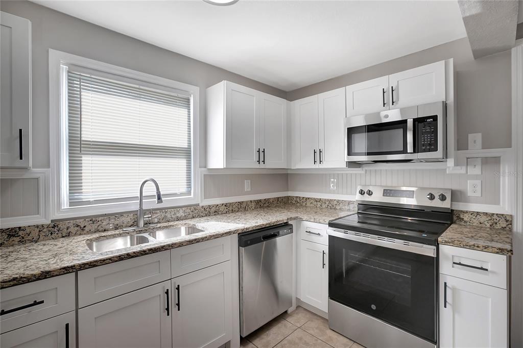 5605 Oceanic Road Holiday, FL 34690 - Photo 14 of 36 a kitchen with granite countertop a sink cabinets and stainless steel appliances