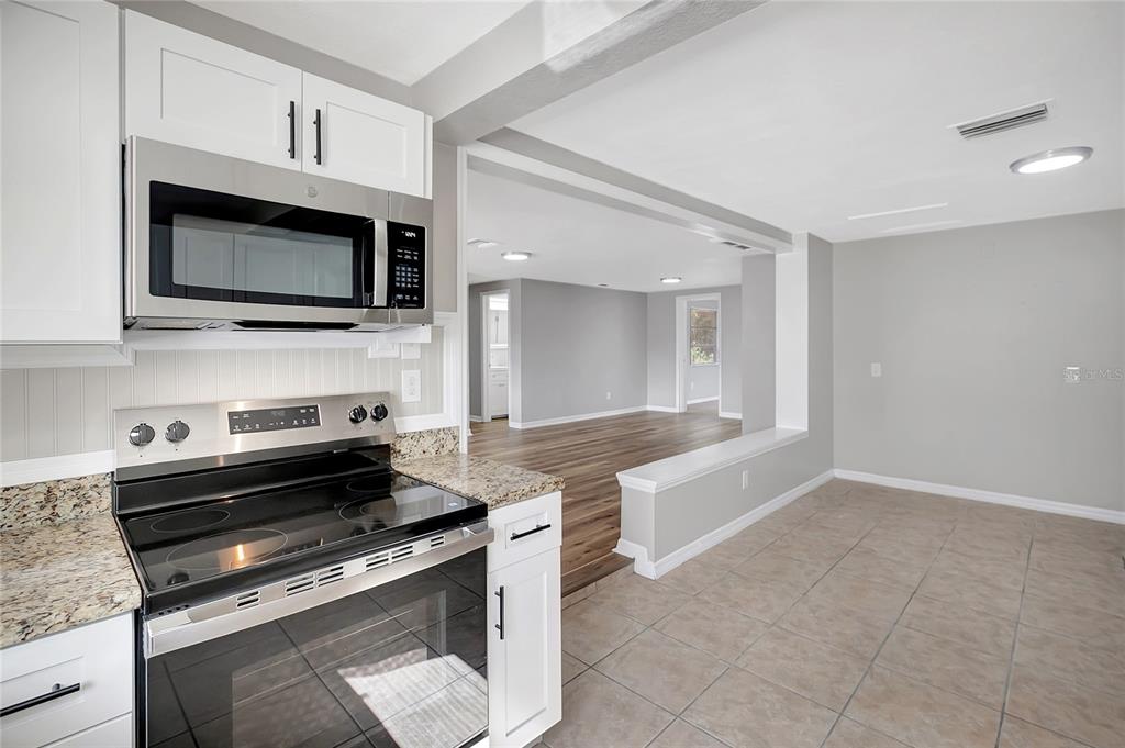 5605 Oceanic Road Holiday, FL 34690 - Photo 15 of 36 a kitchen with granite countertop a stove and a microwave