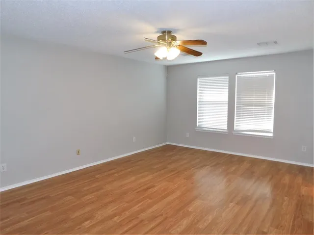 a view of an empty room with a chandelier fan and a window