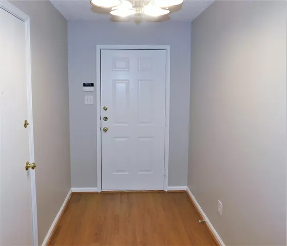 a view of a small space with wooden floor and a chandelier fan