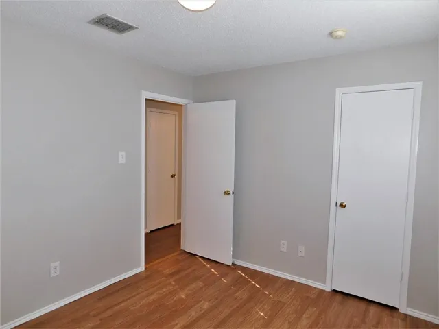 an empty room with wooden floor and closet