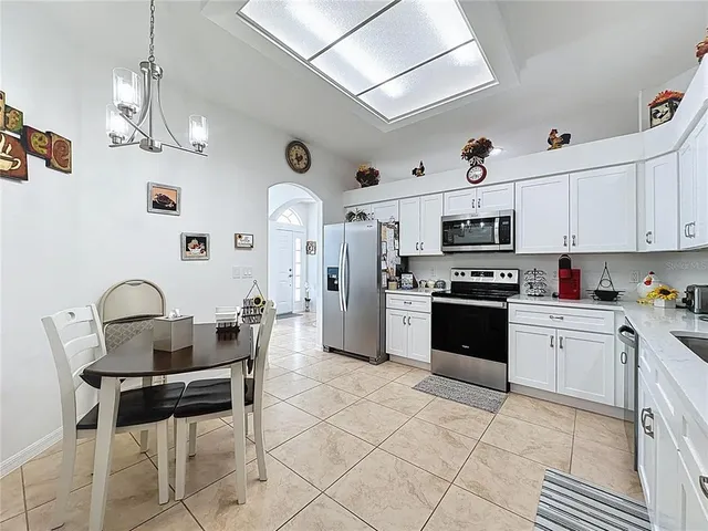 a kitchen with stainless steel appliances kitchen island granite countertop a table chairs and a refrigerator
