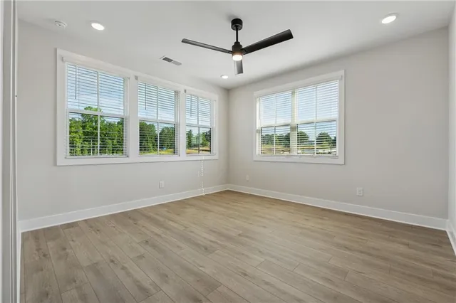 an empty room with wooden floor and windows