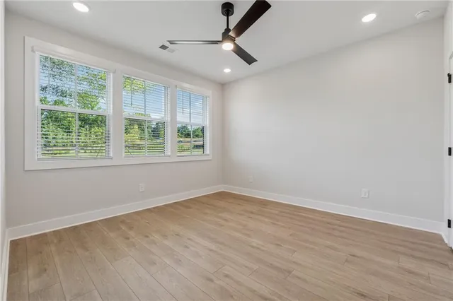 a view of an empty room with wooden floor and a window